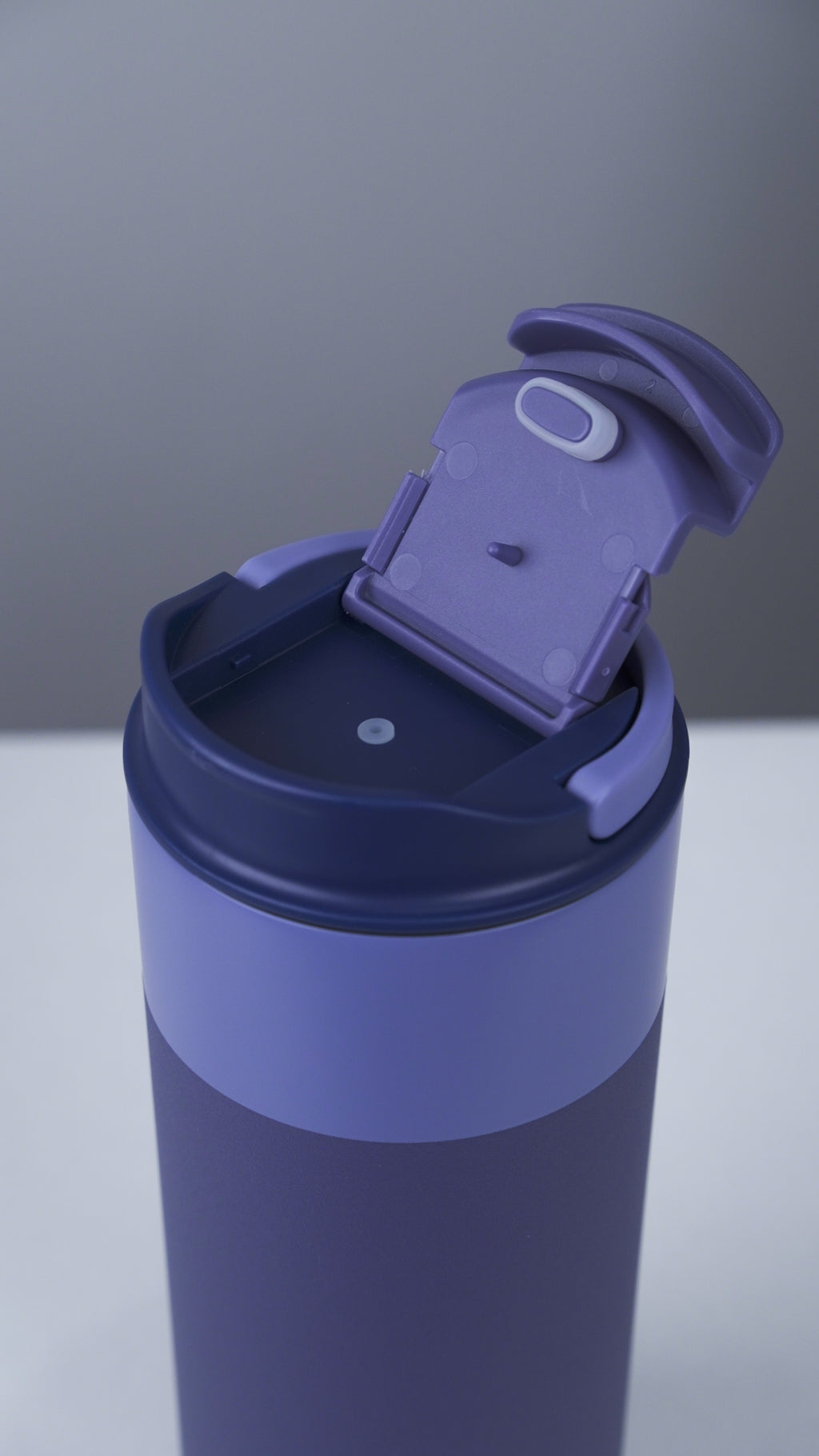 Blue tumbler with a purple lid on a gray background