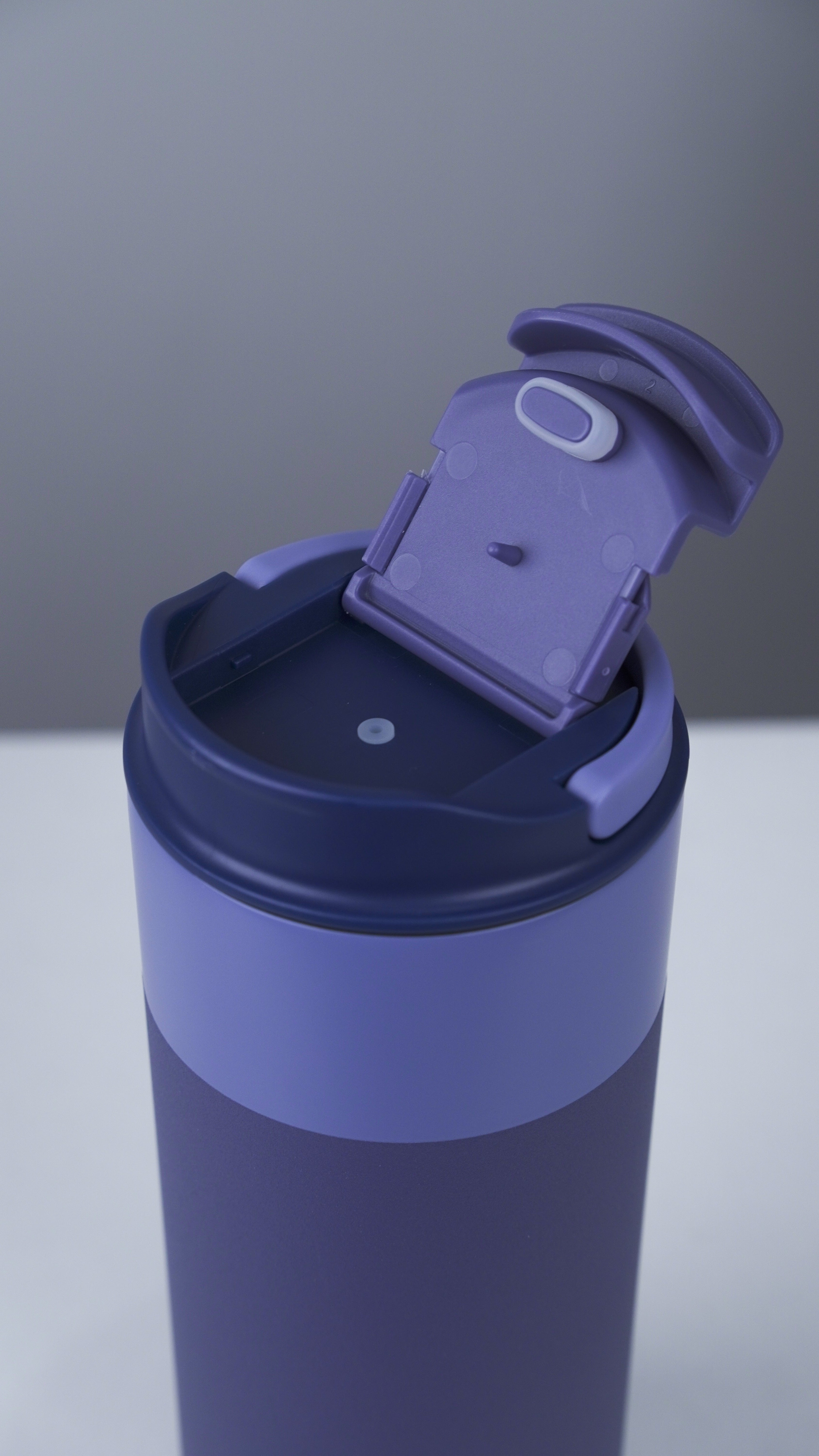Blue tumbler with a purple lid on a gray background